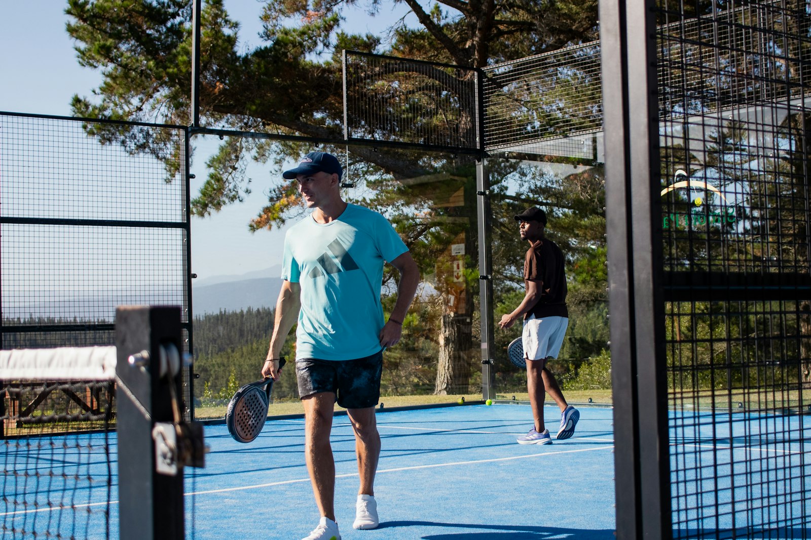 Två spelare i en padelmatch på en blå bana